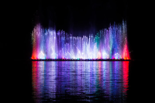 Beautiful fountain dancing show with reflection on water at night.