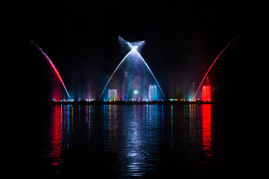 Beautiful fountain dancing show with reflection on water at night.