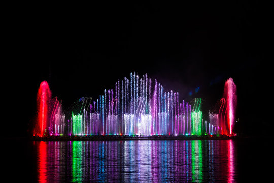 Beautiful fountain dancing show with reflection on water at night.