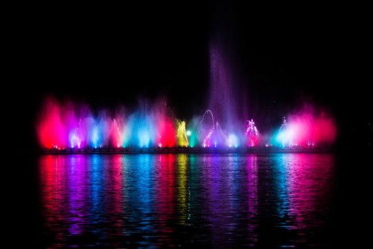 Beautiful fountain dancing show with reflection on water at night.