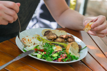 Man eats meat, rice and vegetables at a wooden table