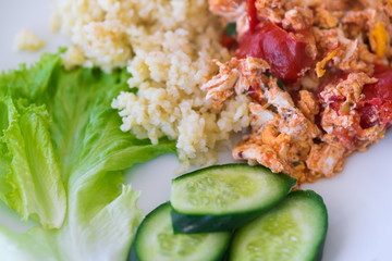 Rice with meat, lettuce and cucumbers on a white plate