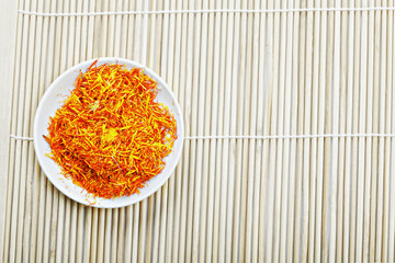 Saffron leaves spice in saucer on mat above view