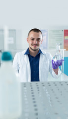 Modern chemist looking at liquid in flask in laboratory