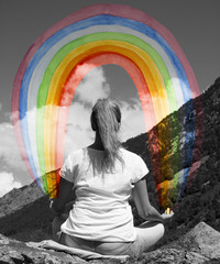 Obraz na płótnie Canvas A young girl meditating on a mountaintop with a rainbow in the h
