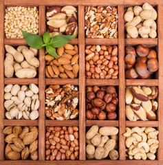 Assorted whole and peeled nuts in wooden box isolated.