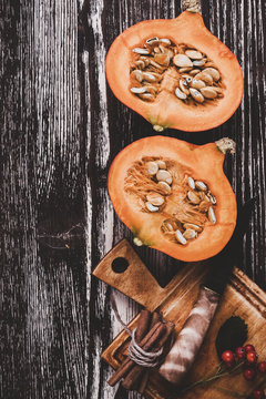 Halved fresh pumpkin on  rustic wooden table with copyspace 