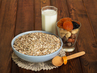 Bowl oatmeal, glass milk and spoon on background dark wood.