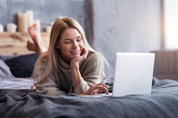 Fototapeta premium Pretty woman using laptop in bedroom