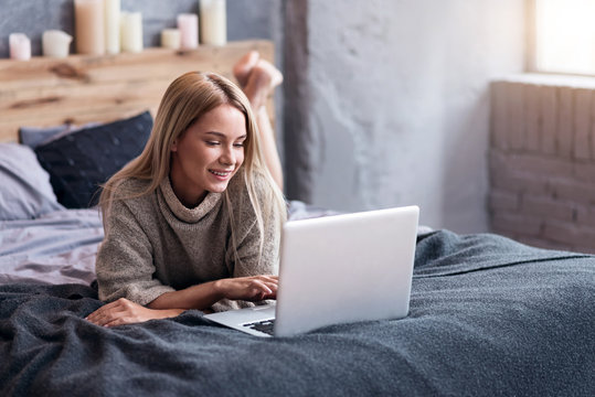 Beautiful woman lying in bed with a laptop - Powered by Adobe