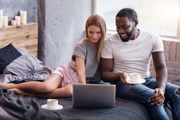 Sweet couple lying in bedroom with laptop
