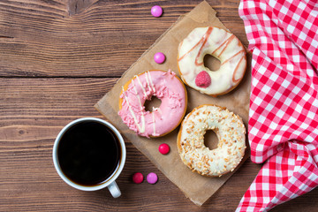 Colorful donuts, smarties and cup of coffee, wooden background, top view