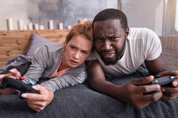 Fototapeta premium Amused couple playing video games in bedroom together