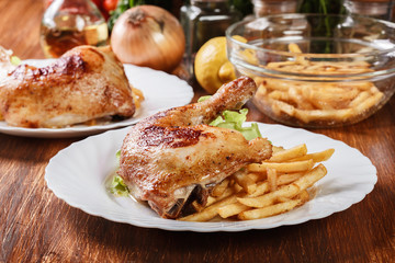 Roasted chicken legs with french fries and lettuce