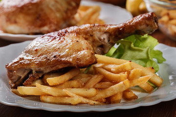 Roasted chicken legs with french fries and lettuce