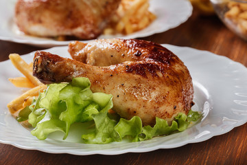 Roasted chicken legs with french fries and lettuce