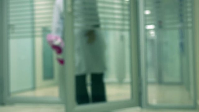 Defocused lab worker wearing white gown entering clinical laboratory 4K video