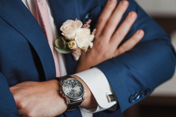 Midsection closeup of confident groom with arms crossed on his chest. Focus on luxury watch at wrist