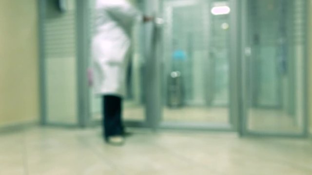 Blurred lab worker wearing white gown leaving hospital laboratory 4K video