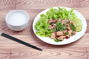 Rice gruel and spicy  vegetable salad with canned tuna served .