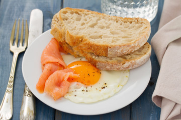 fried egg with smoked salmon and bread on white dish