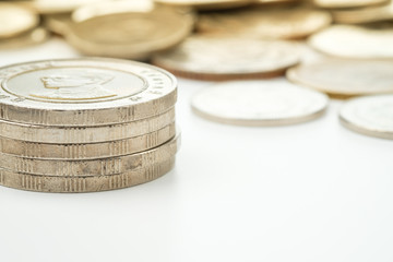 Thailand ten baht coins stacked with many coins blur on white ba