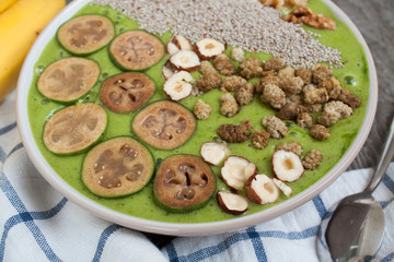 Detox healthy green smoothie bowl with bananas and feijoa, chia, mulberry, nuts, avocado