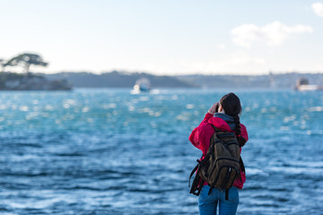 Woman photographer taking pictures of moving boat and harbour