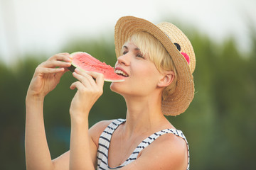 Beautiful girl in straw hat eating fresh watermelon. Film camera style