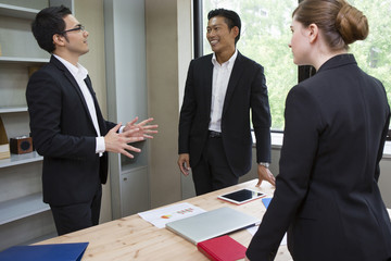 机を囲んで話すビジネスパーソン