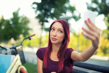 Red-haired girl sitting on the bench make selfie