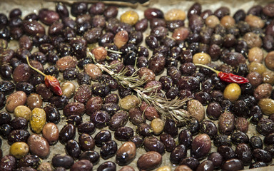 Baking fresh, colorful, organic olives, with rosemary, red hot peppers and mediterranean herbs, close-up, selective focus, space for text