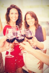 Composite image of cropped image of hand holding wine glasses