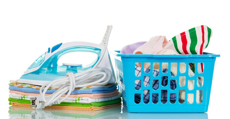 Steam iron, pile towels and plastic basket with clothes isolated.