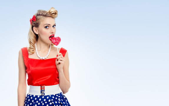 young woman eating colourful lollipop, dressed in pin-up style