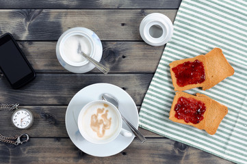 Foods of the Italian breakfast with coffee milk and rusks with jam on an old wooden table