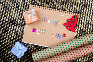 Notepad with the inscription "Happy New Year", gift boxes and wrapping paper