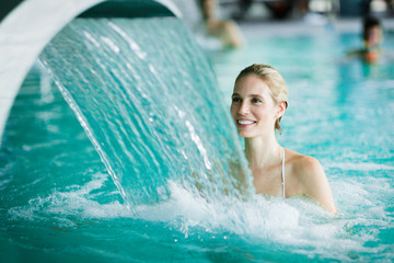 Woman enjoying hydrotherapy in spa pool - obrazy, fototapety, plakaty