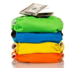 Stack modern cloth diapers and dollars isolated on white background.