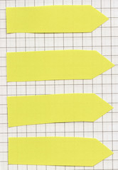 Set of arrow shaped yellow reminder notes on squared paper background