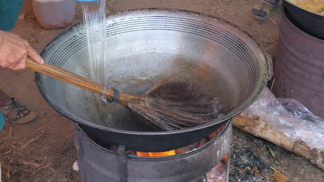 close up of a man washing a hot wok cooking with a broomstick