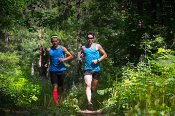 Naklejka na ściany i meble Trail running athletes moving through the forest