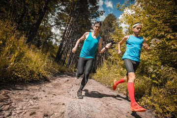 Trail running athletes crossing off road terrain at sunny day