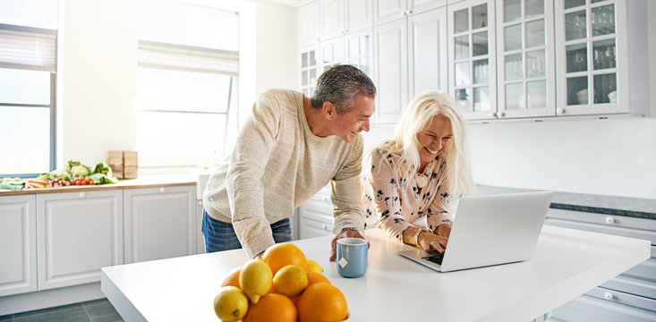 Senior couple relaxing in a kitchen with a laptop