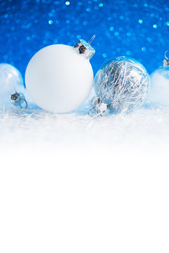 Silver and white xmas ornaments on white and blue glitter bokeh background. Merry christmas card. Winter holiday theme. Happy New Year. Space for text.