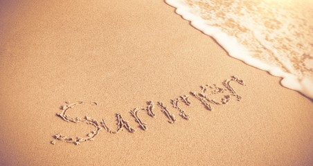 Summer written on sand with surf 