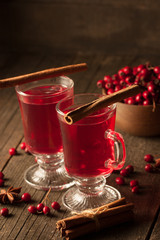 Two cups of red hot tea drink with fruits and spices on a wooden background. Mulled wine with cinnamon, anise and red berries. Winter hot drinks concept.