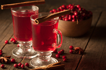 Two cups of red hot tea drink with fruits and spices on a wooden background. Mulled wine with cinnamon, anise and red berries. Winter hot drinks concept.