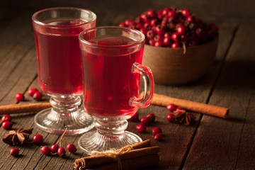 Two cups of red hot tea drink with fruits and spices on a wooden background. Mulled wine with cinnamon, anise and red berries. Winter hot drinks concept.