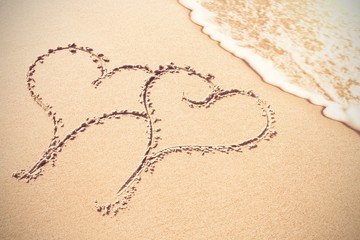 Two heart shapes inscribe on sand